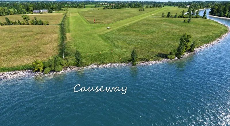 Grass airstrip with windsock and marker cones beside the water at Causeway in Microsoft Flight Simulator