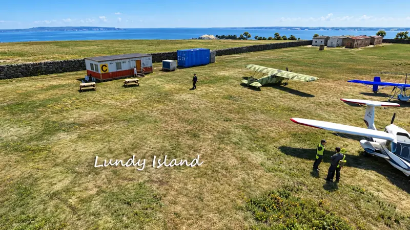 Aircraft parked on the clifftop grass airstrip on Lundy Island with the sea behind, in Microsoft Flight Simulator