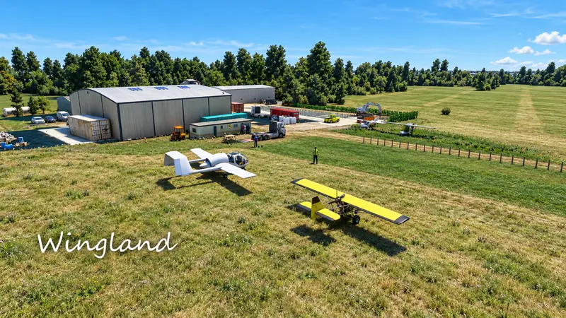 Yellow microlight and light aircraft on the grass by the hangar at Wingland in Microsoft Flight Simulator
